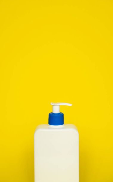 Liquid container for gel, lotion, cream, shampoo, bath foam. Cosmetic plastic bottle with dispenser pump on yellow background. Cosmetic packaging mockup with copy space - Fotoğraf, Görsel