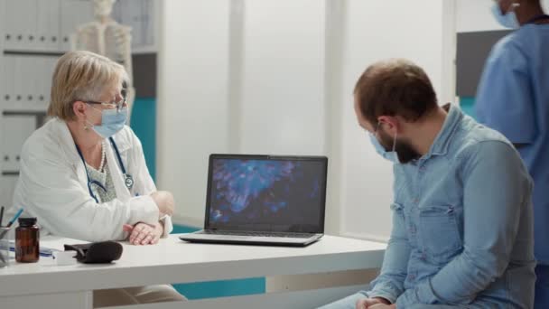 Physician analyzing virus animation on laptop with sick patient during covid 19 pandemic in checkup cabinet. Examination of coronavirus illustration for prevention and recovery on computer. - Footage, Video