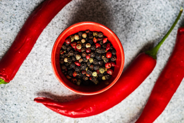 Schaal met peper kruidenmix en rode hete chili peper groente op grijze betonnen tafel - Foto, afbeelding