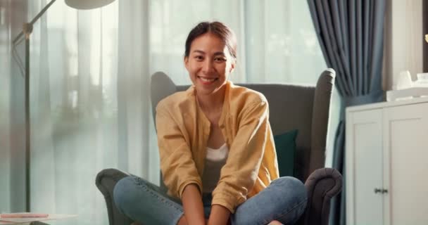 Youth asia female girl or university student sit on sofa chair Relaxed serene take a rest, happy calm lady dream enjoy wellbeing breathing fresh air  in living room at house. Home lifestyle concept. - Filmmaterial, Video
