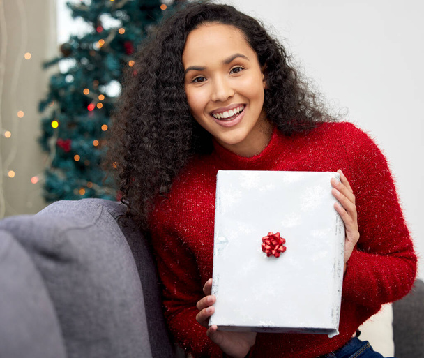 De beste manier om kerstvreugde te verspreiden is luid zingen voor iedereen om te horen. een jonge vrouw opent cadeautjes tijdens Kerstmis thuis - Foto, afbeelding