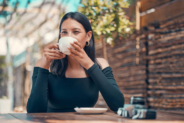 Calm, relaxed and stylish woman taking a coffee break at an outdoor coffee shop in summer. One young entrepreneur or freelancer enjoying her free time drinking tea and relaxing outside. - Foto, immagini