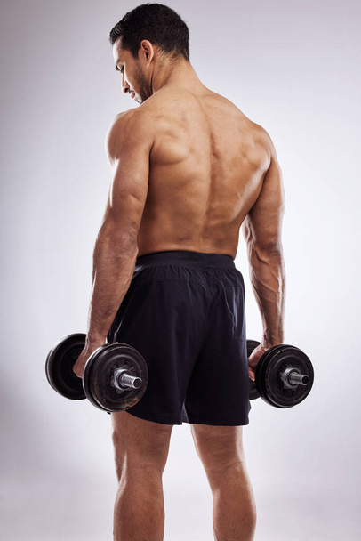 Dont neglect your back muscles. a man holding dumb bells against a studio background - Foto, immagini