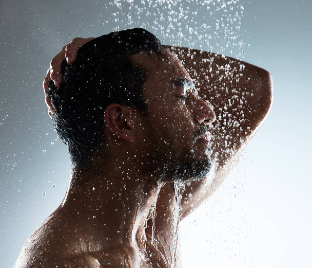 Life is incoherent, accept its flow. Studio shot of a young man washing his hair in a shower against a grey background - Fotoğraf, Görsel