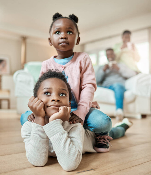 The bond between brother and sister. Full length shot of an adorable little girl sitting on her brothers back on the living room floor at home - Fotoğraf, Görsel