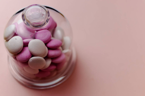 Pink and white peppermint candies in a glass jar on a pink background - Foto, Imagem