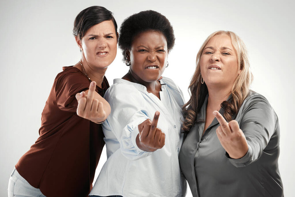 We couldnt care less what you think. a diverse group of women standing together in the studio and pulling the middle finger - Foto, Imagem
