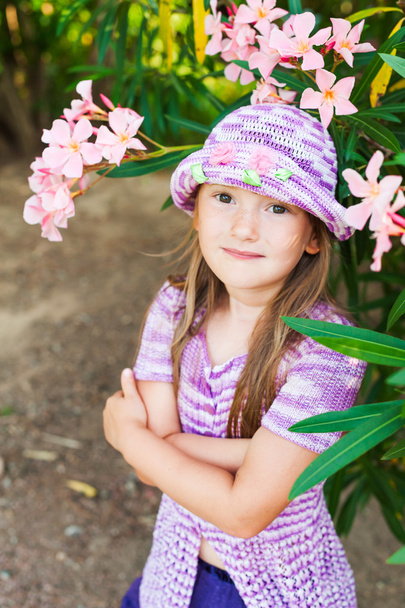 Close up portrait of a cute little girl in a beautiful knitted violet hat with flowers - Foto, immagini