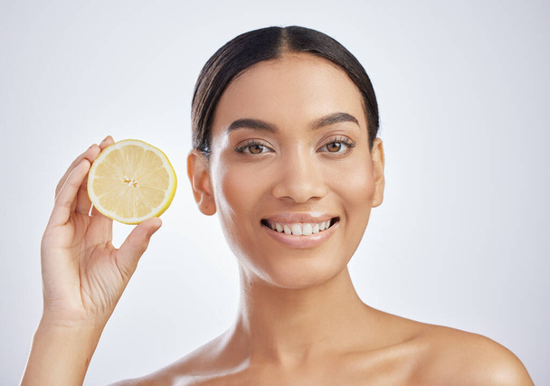 Afscheid nemen van vlekken met vitamine C. Studio shot van een aantrekkelijke jonge vrouw met een citroen tegen een grijze achtergrond - Foto, afbeelding