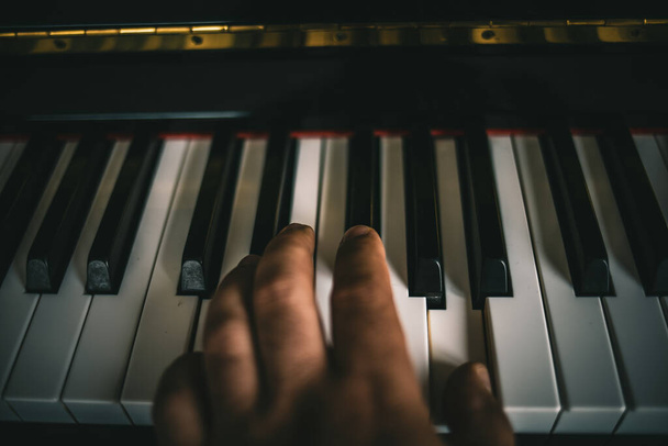 A closeup shot of a hand on the piano's keys playing amazing music - Foto, afbeelding