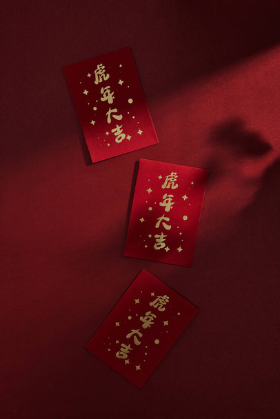 A vertical shot of Chinese red envelopes for money isolated on a dark red background - Foto, Imagen