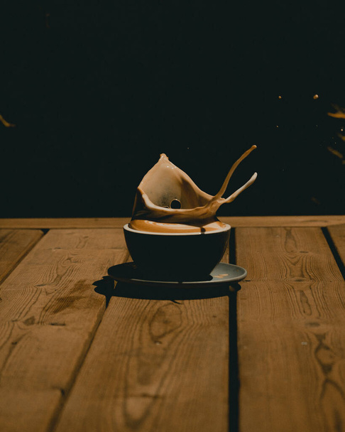 Egy függőleges közelkép egy bögre cappuccinóról kávéval a fa asztalon. - Fotó, kép
