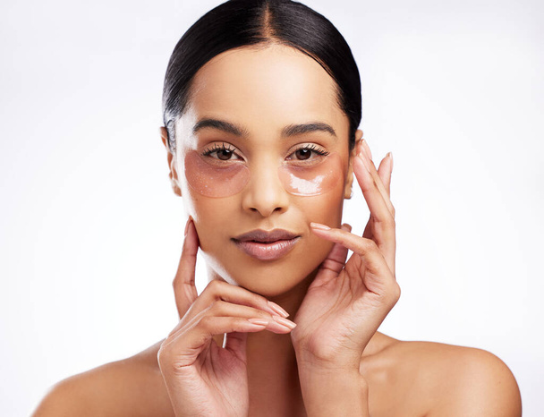 Targeting dark circles and fine lines for smoother skin. Studio portrait of a beautiful young woman wearing under-eye patches against a white background - Foto, immagini