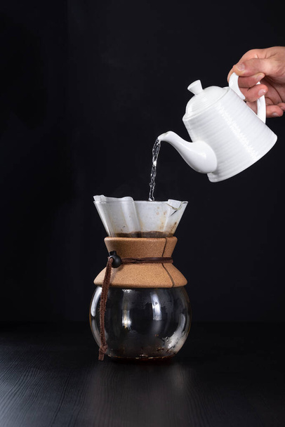 A vertical closeup of the coffee brewing on black background. - Фото, зображення