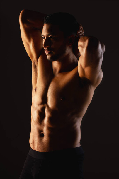 Move your body, grow your muscles. Studio shot of a fit young man posing against a black background - Photo, Image