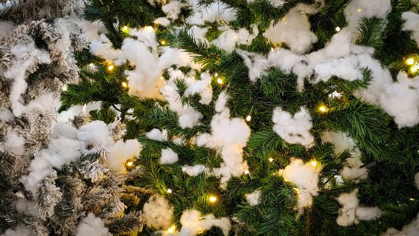 A shot of snow on a Christmas tree with yellow decorative lights for a background - Zdjęcie, obraz