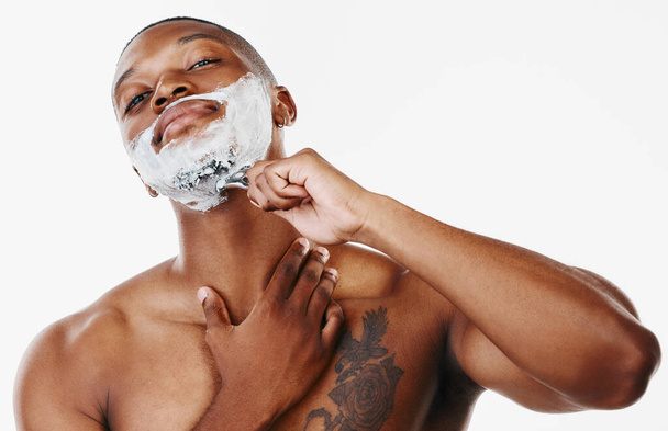 Too many days in a daze, better wake up. Studio shot of a handsome young man shaving his facial hair with a razor against a white background - Photo, Image