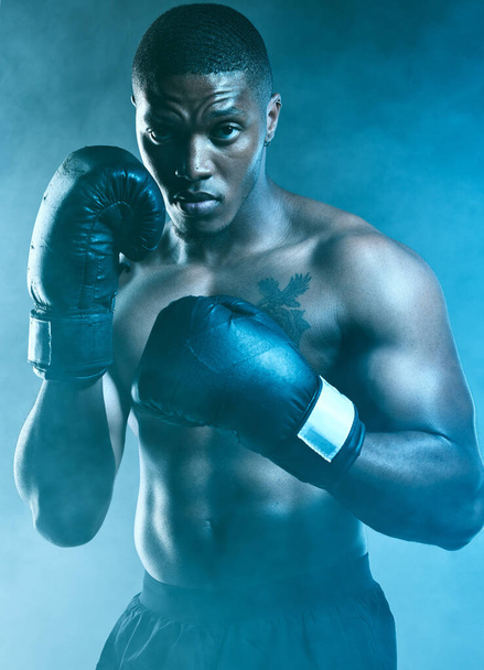 Show me what you got. Studio shot of a handsome young man boxing against a blue background - Zdjęcie, obraz