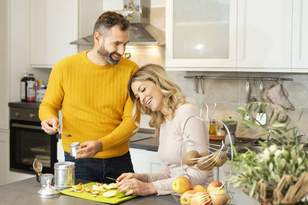 Happy couple in the kitchen. Romantic young couple preparing fresh fruit and coffee. Healthy life and love. Smiling people living together. - 写真・画像