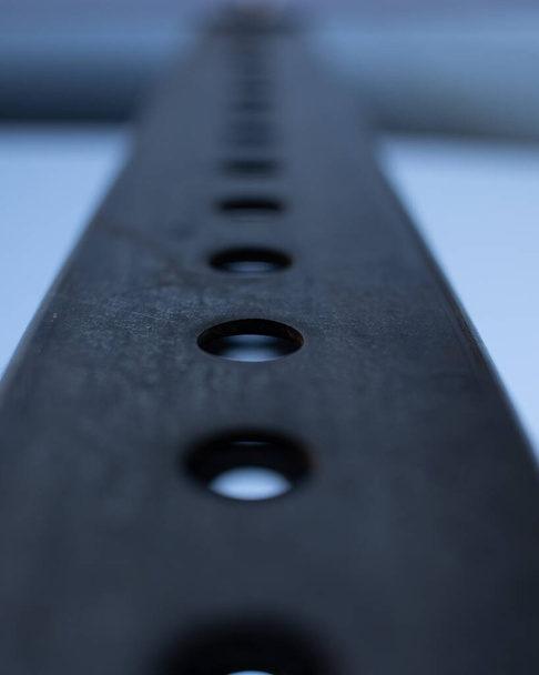 Eine vertikale Aufnahme einer Metalloberfläche mit Löchern auf verschwommenem Hintergrund - Foto, Bild