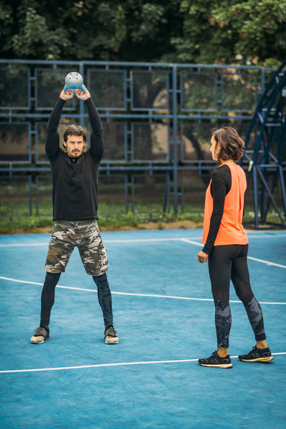 Fit and healthy personal trainer showing kettlebell exercise to a female client. - Foto, Imagen