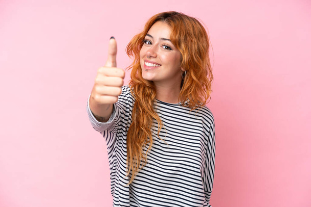 Young caucasian woman isolated on pink background with thumbs up because something good has happened - Photo, Image