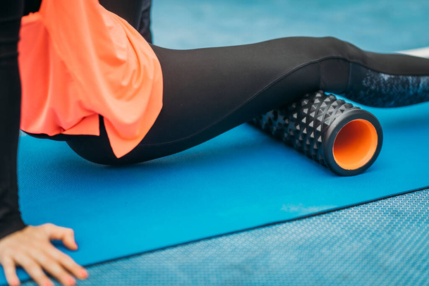 Close up image of attractive female athlete, stretching with foam roller, outdoors - Φωτογραφία, εικόνα