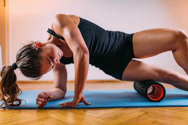 Sporty Woman Self Massaging Legs with Foam Roller at Home - Photo, image