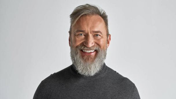 Portrait of senior smiling caucasian man looking at camera. Stylish bearded pensioner wearing casual clothes. Modern elderly male lifestyle. Isolated on white background. Studio shoot. Copy space - Фото, изображение