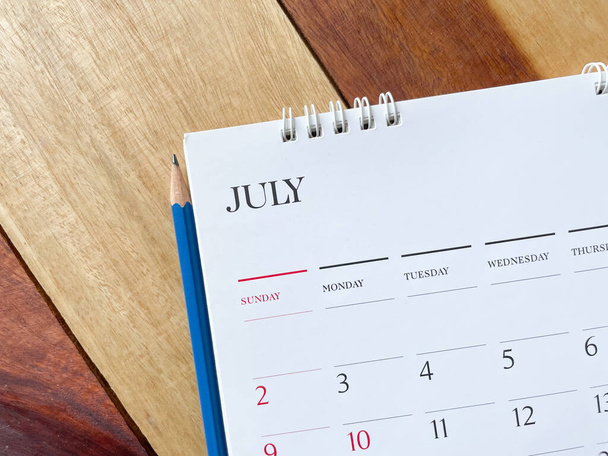 Calendar July with pencil on wood texture.inPlanning concept. - Фото, зображення