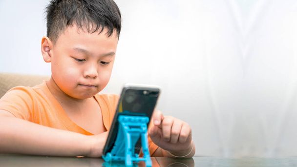 lapsi käyttää puhelinta pöydällä lapsi teknologia lapsuuden käsite - Valokuva, kuva