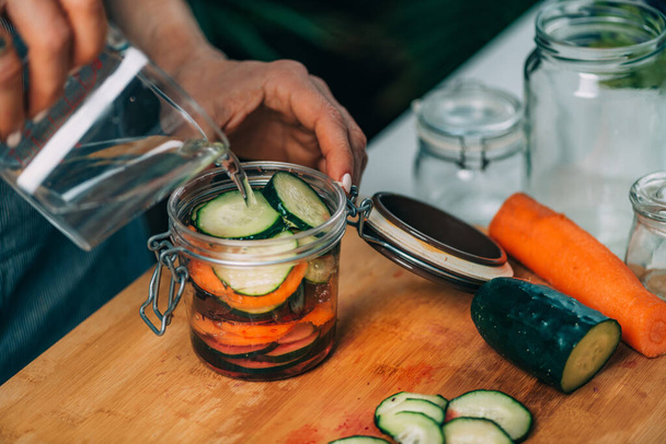 Homemade fermented vegetables. Woman pouring water in the jar with vegetables. Vegetable Fermentation Process. - 写真・画像