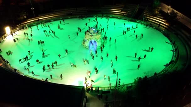 Luchtdrone zicht vlucht over een ijsbaan onder een open hemel met licht en muziek, waarop veel mensen 's nachts schaatsen in de winter. Animatie, vrije tijd, vakantie. Nieuwjaar Kerstmis - Video