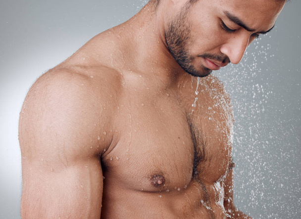 Admiring himself. a young man taking a shower against a grey background - 写真・画像