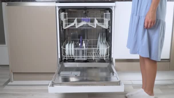 Una mano de ama de casa empuja hacia fuera el estante superior vacío del lavavajillas con el estante inferior cargado. Imágenes de alta calidad 4k - Metraje, vídeo