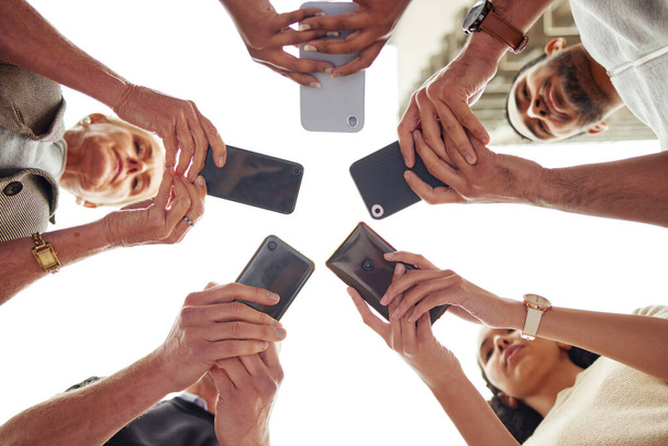 Everyone has a connection to make. Low angle shot of a group of unrecognisable people using their cellphones in synchronicity - Foto, afbeelding