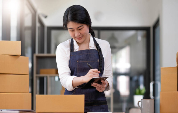 Portrait, entrepreneur, young Asian woman, freelance business, sme business, online shopping, working on laptop computer with parcel box on home office table, online business and delivery concept - Zdjęcie, obraz