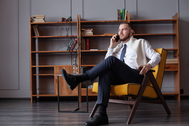 Веселый бизнесмен в рубашке делает телефонный звонок в помещении - Фото, изображение