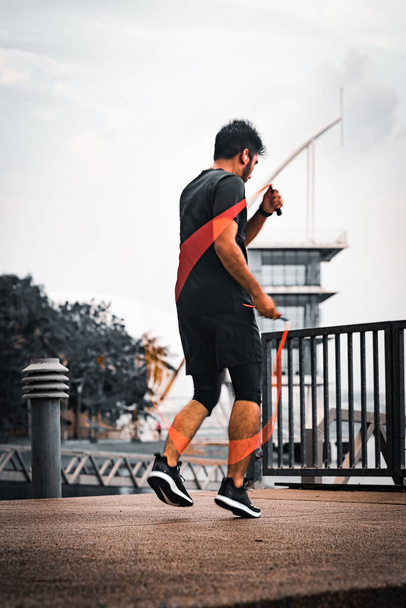 Kuala Lumpur, Malaysia - April 5, 2022 - Asian sportsman training with jumping rope in the park. - Foto, imagen