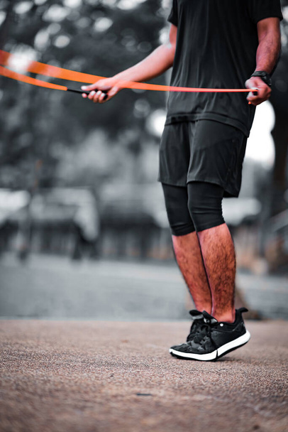 Fitness concept. Healthy lifestyle. Man in black jumping with skipping rope in the park. - Foto, Imagen