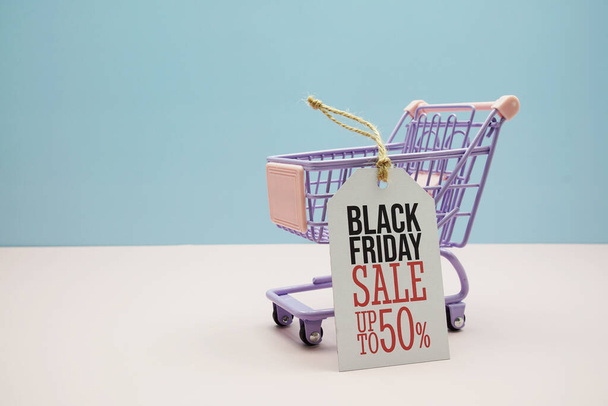 Black Friday Sale 50% text message and shopping trolley cart on blue and pink background - Photo, image