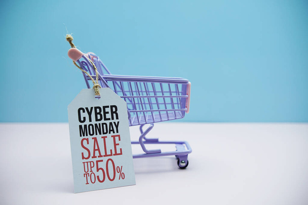 Cyber Monday Sale 50% text message and shopping trolley cart on blue and pink background - Фото, изображение