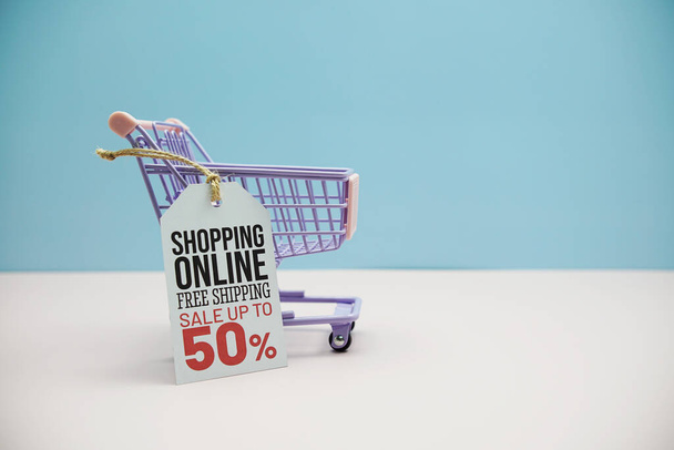 Shopping Online Sale 50% text message on price tax with shoppint trolley cart on blue and pink background - Foto, Imagem