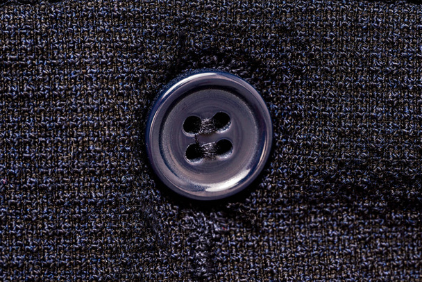 Macro photo of a sewing button on a dark blue fabric pattern isolated background. High quality photo - Photo, Image