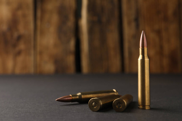 Bullets on black table against wooden background, closeup. Space for text - Foto, Imagem