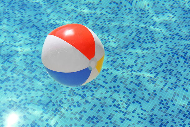 Inflatable beach ball floating in swimming pool, space for text - Zdjęcie, obraz