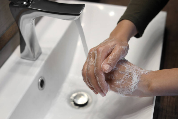 Woman washing hands in sink, closeup view - Фото, изображение