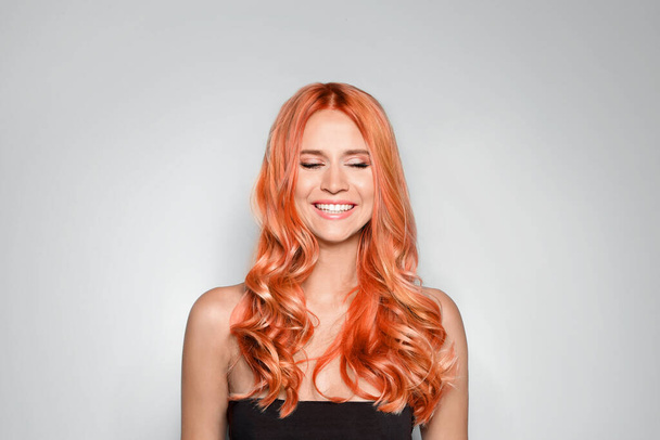 Beautiful woman with long orange hair on light background - Фото, зображення