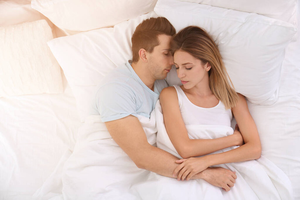 Young couple sleeping on soft pillows in bed at home, top view - 写真・画像