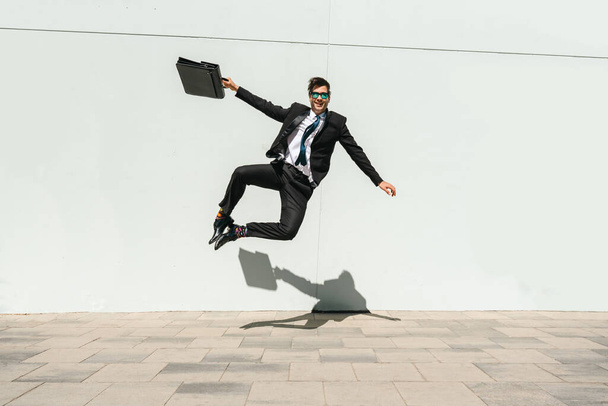 Happy and handsome adult businessman wearing elegant suit doing acrobatic trick moves in the city, alternative concept for business advertisement with energetic and creative people - Φωτογραφία, εικόνα